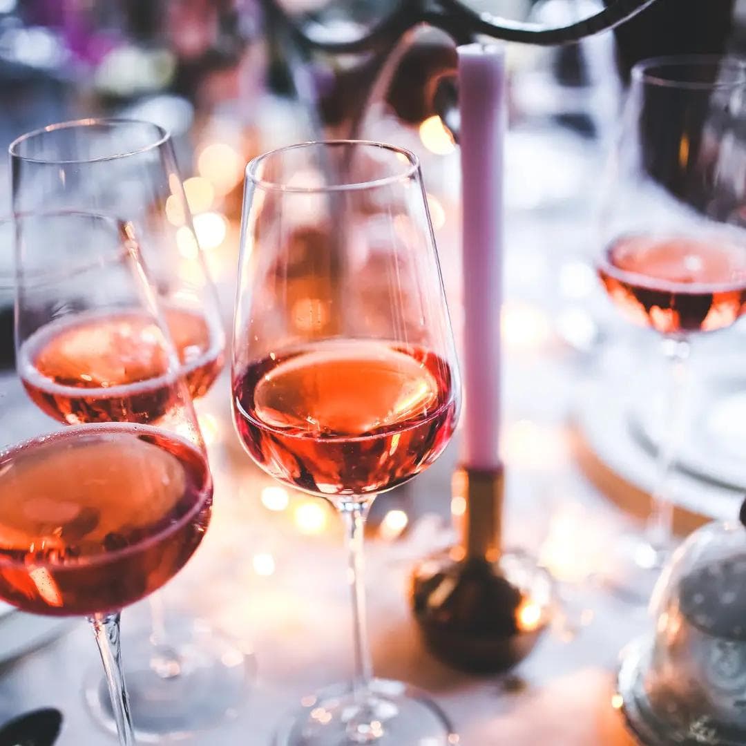 Glasses of rosé wine on a candlelit table with a warm, elegant ambiance.