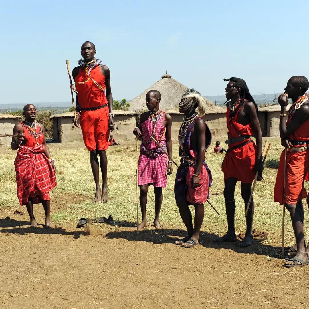 Maasai villagers demonstrating traditional jumping dance in a rural setting.